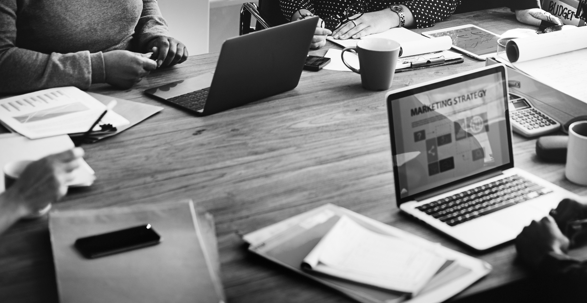 Mesa de trabajo moderna con laptop y equipo trabajando en estrategias digitales